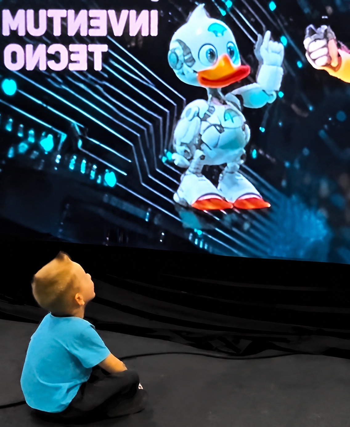 Criança observa o mascote robótico da INVENTUM em uma tela